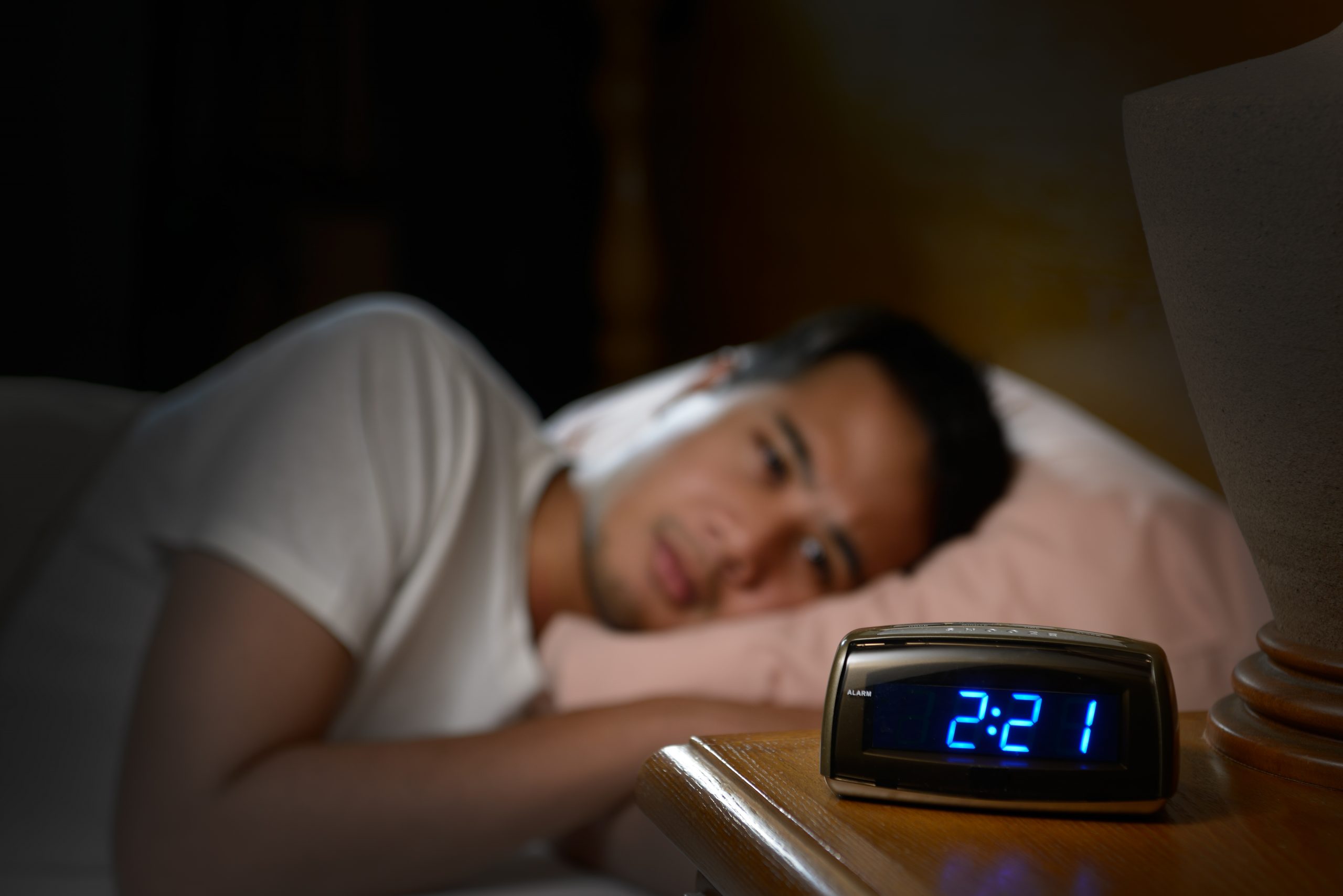 Depressed man suffering from insomnia lying in bed